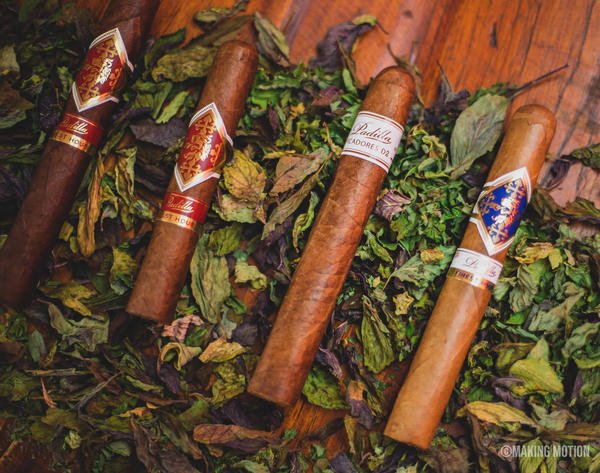 Four cigars on green and dark leaves on a table